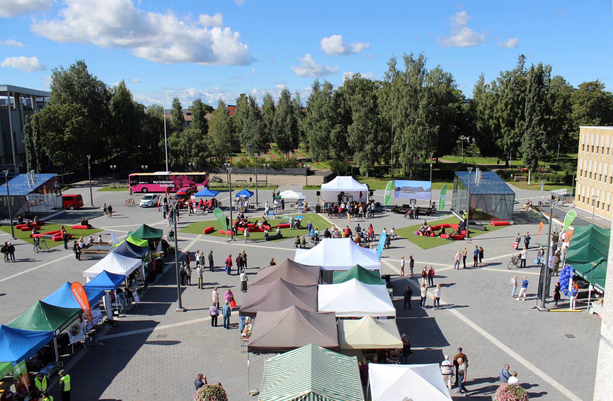 Lappeenrannan Kansalaistori, jossa on telttoja, ihmisiä sekä pinkki linja-auto.   
